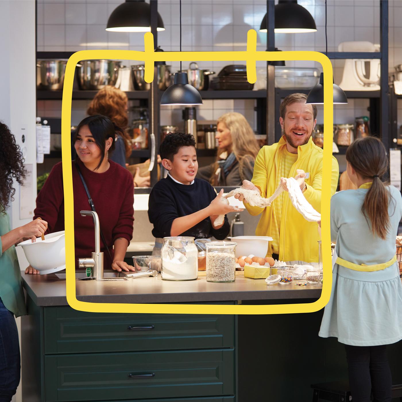 Osobe pripremaju hranu u kuhinji, stoje oko otoka s namirnicama.