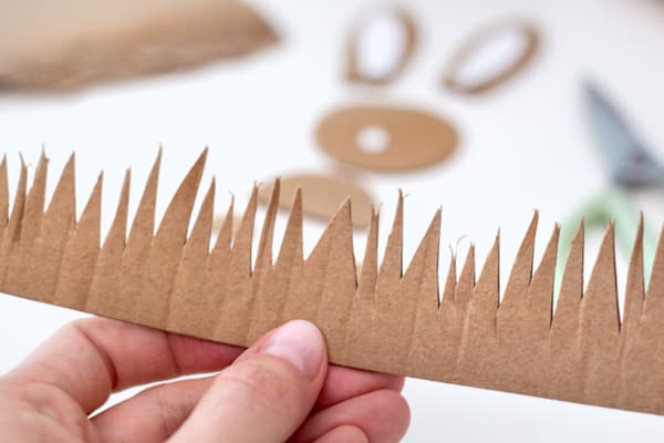 Ostergras wird aus Pappe geschnitten. Ein Streifen in steilem Zickzack ausgeschnitten.
