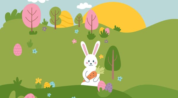 Osterhäschen sitzt mit Karotte im Arm in eine Wiese, in der bunte Ostereier versteckt sind