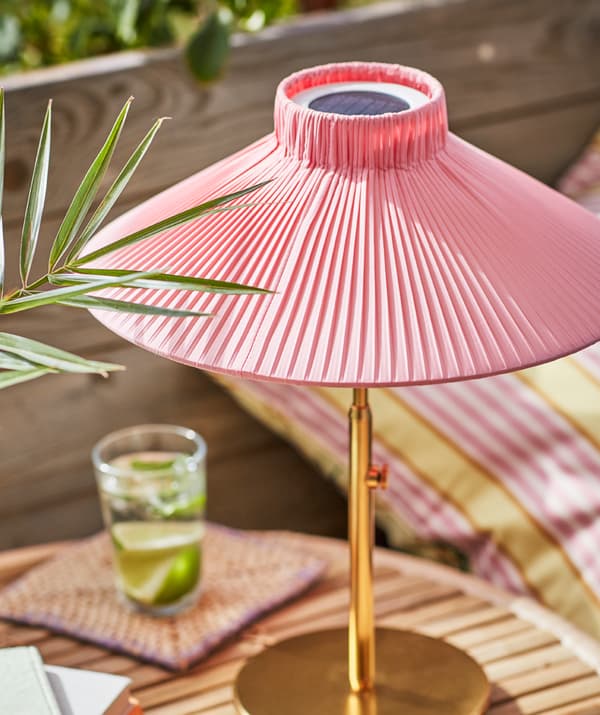Osunčana SOLVIDEN solarna lampa na stočiću, s čašom napunjenom pićem i komadićima limete.