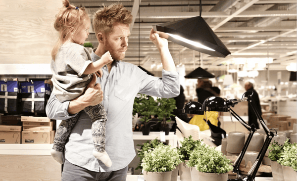 Otac drži ćerku u naručju dok gleda IKEA visilice u robnoj kući