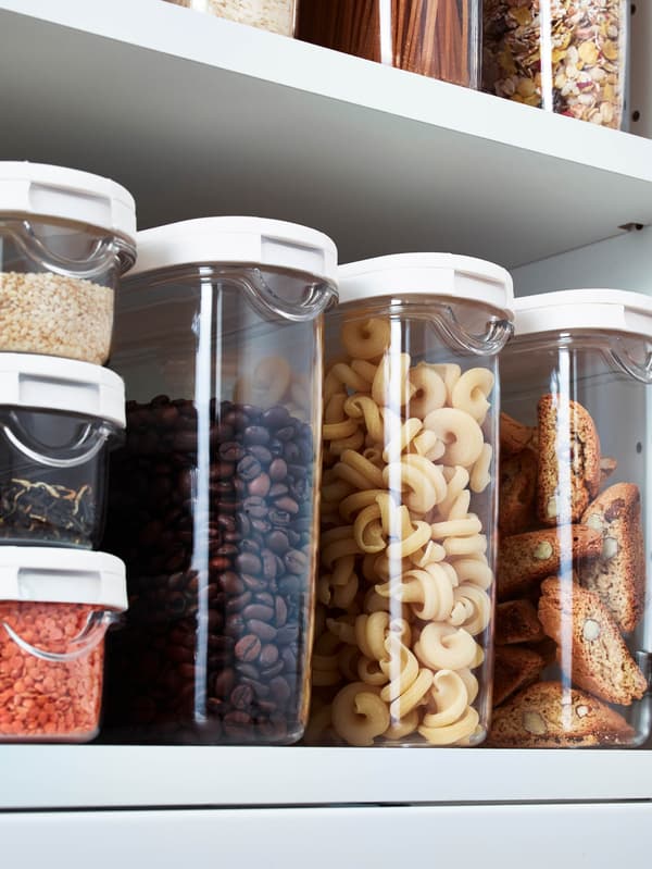Otevřená bílá kuchyňská skříňka plná dóz IKEA 365+ se suchými potravinami.