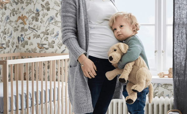 Otrok s plišastim kužkom v naročju se stiska k mamici.