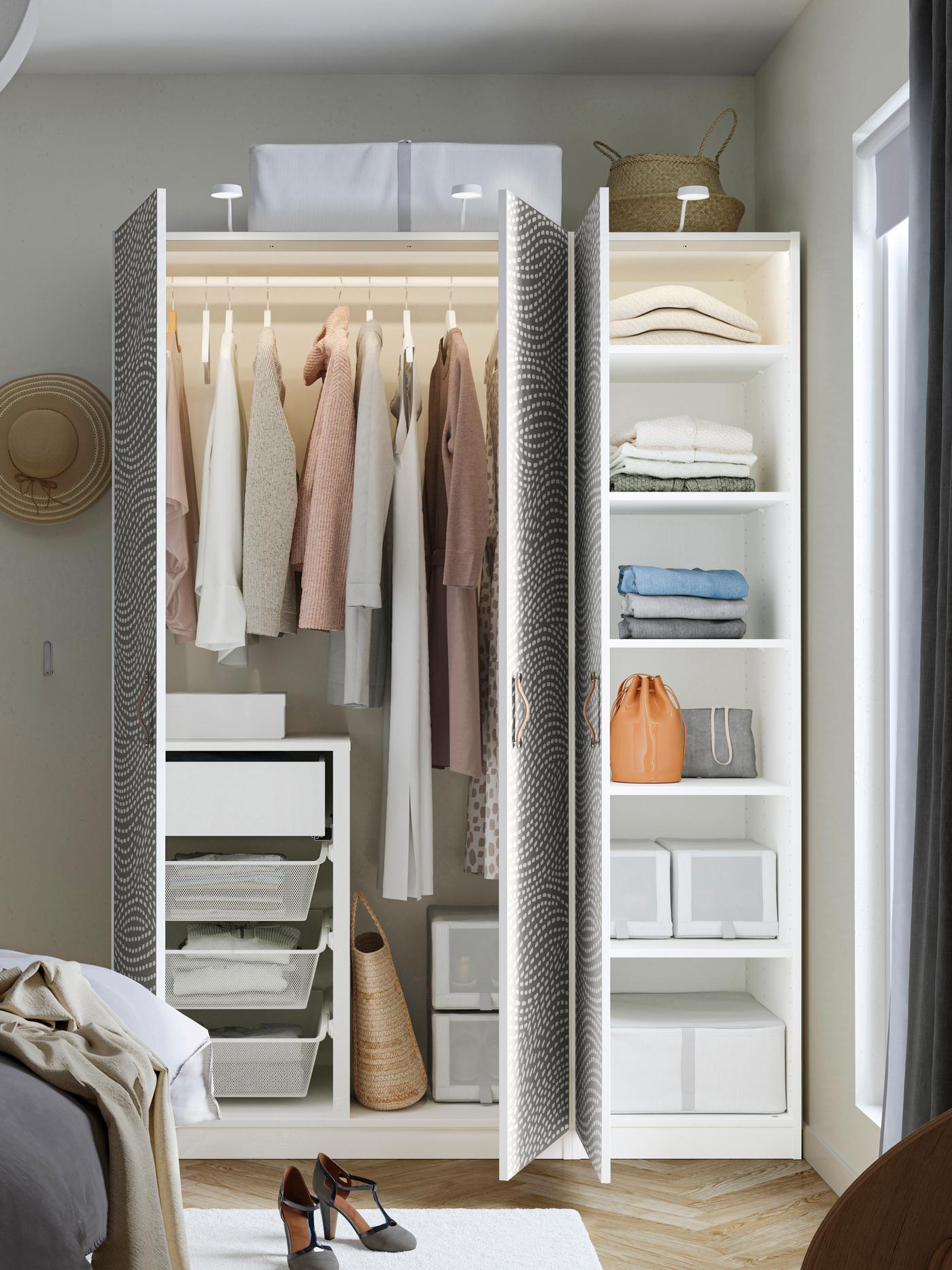 Otvorená biela skriňa s vešiakmi a zásuvkami vo vnútri.