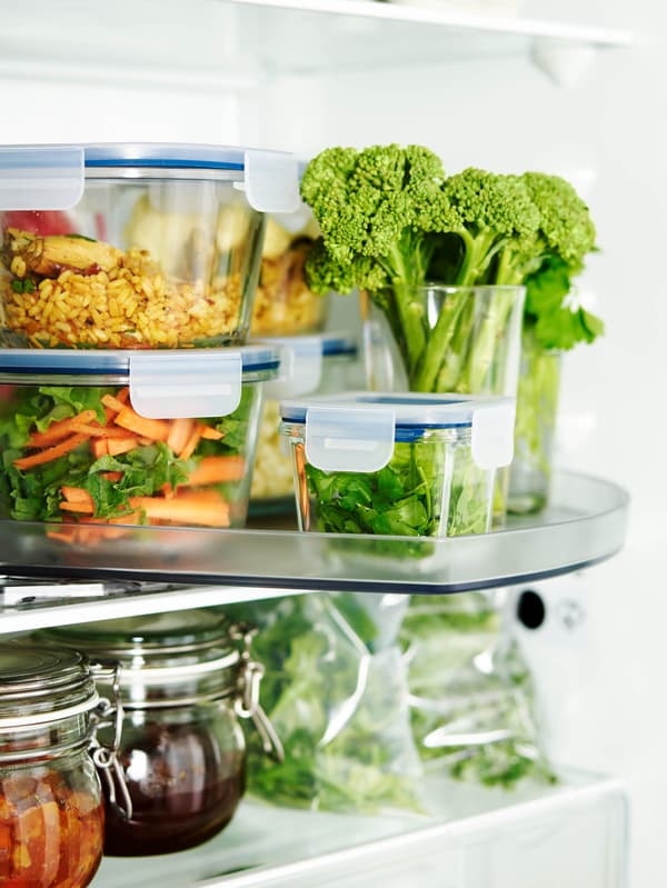 Otvorená chladnička s potravinami v dózach IKEA 365+ na otočnom podnose SNURRAD a v dózach KORKEN.