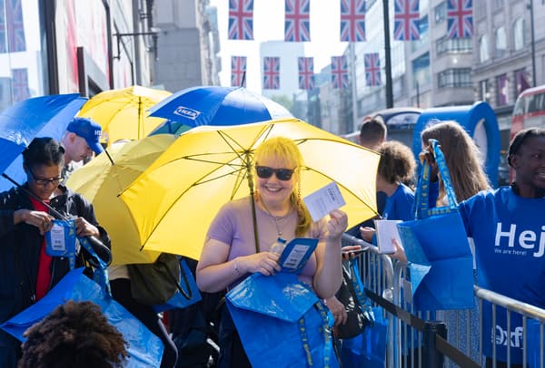 Outside look of customers waiting with yellow and blue umbrella