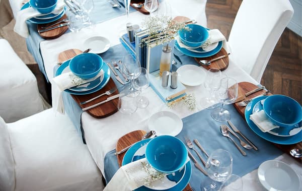 Overhead view of a dining table with formal table settings in white and blue.