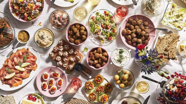 Overhead view of a table filled with assorted dishes, including meatballs, salads, seafood, bread, and desserts.