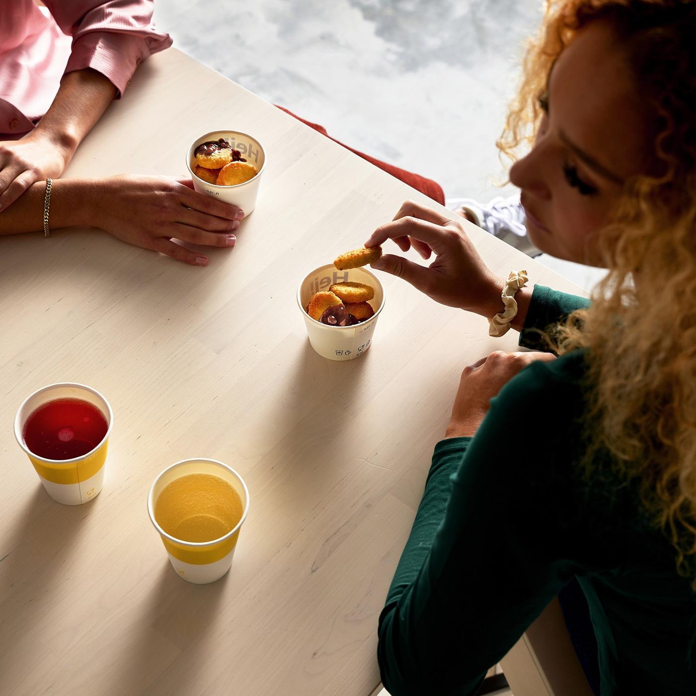 Overhead view of two people sitting at a table, socialising, enjoying fruit slices and soft drinks.
