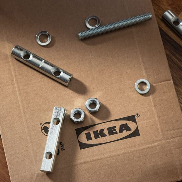 På en IKEA papkasse ligger forskellige møtrikker skruer og bolte til at samle et IKEA møbel med