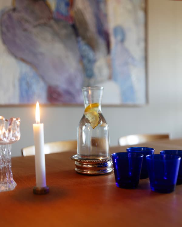 På ett bord står en vattenkaraff och fyra blå glas. 