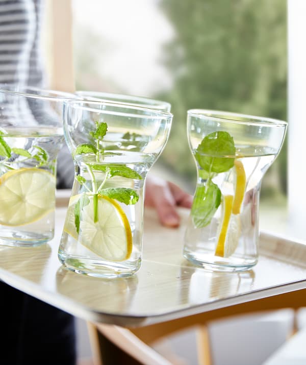 Pahare OMTÄNKSAM ușor de ținut umplute cu apă, felii de lămâie și frunze verzi pe o tavă anti alunecare.