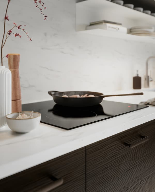 Panel dinding/permukaan atas kerja kesan marmar putih, bahagian hadapan dapur kesan kayu ash berwarna coklat gelap, hob aruhan dan kuali besi tuang.