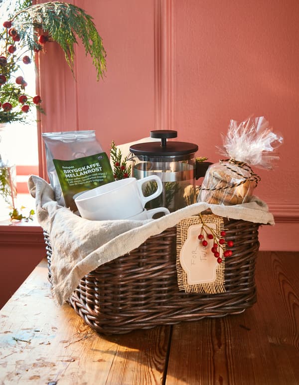Panier cadeau avec un paquet de café, une cafetière, des mugs et des biscuits à l'avoine.