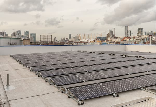 Panneaux solaires sur un toit avec la ville se profilant à l'arrière.