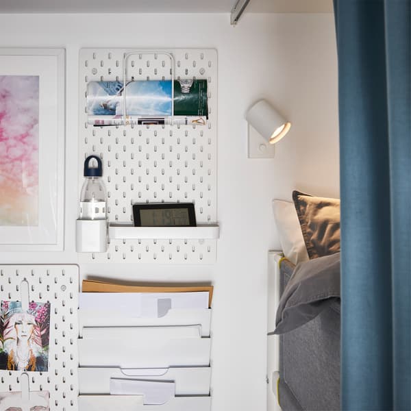 Pannelli portaoggetti bianchi fissati alla parete accanto a un letto a soppalco – IKEA