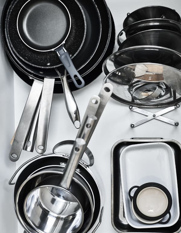 Pans and lids stacked in a drawer.