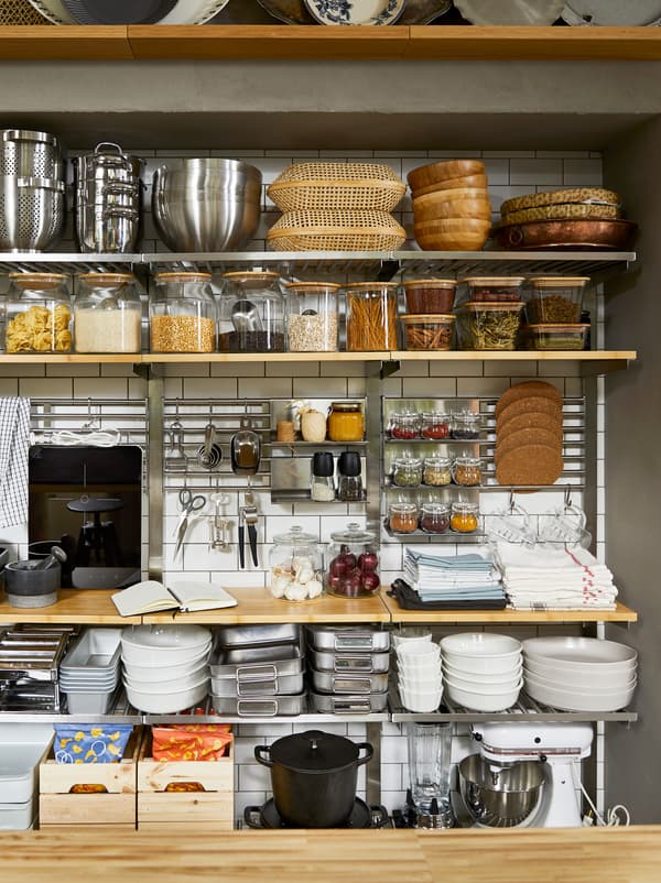 Pantry-style, open-storage kitchen wall with KUNGSFORS shelves, filled with dry goods in jars and cooking accessories.