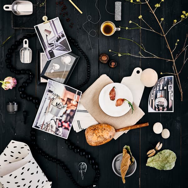 Papan emosi pada latar belakang kayu berwarna hitam dengan piring OFTAST berwarna putih, tekstil berwarna putih dengan tompok berwarna hitam, kopi espreso dan daun.