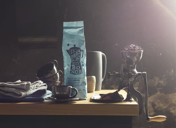 Paquet de café, mugs et moulin à café ancien rempli de grains de café.