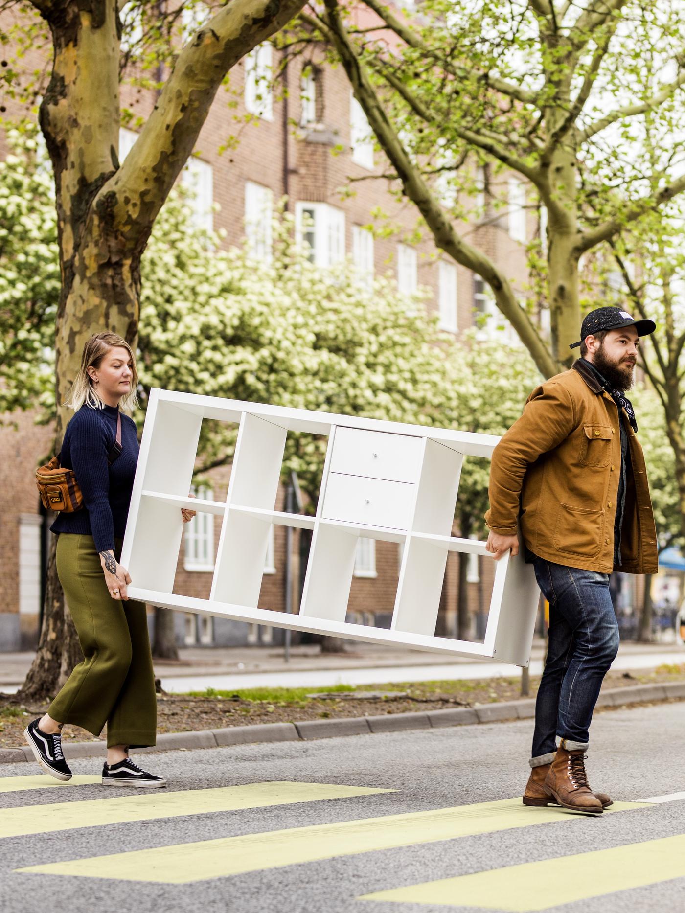 Para niosąca przez przejście dla pieszych regał KALLAX.