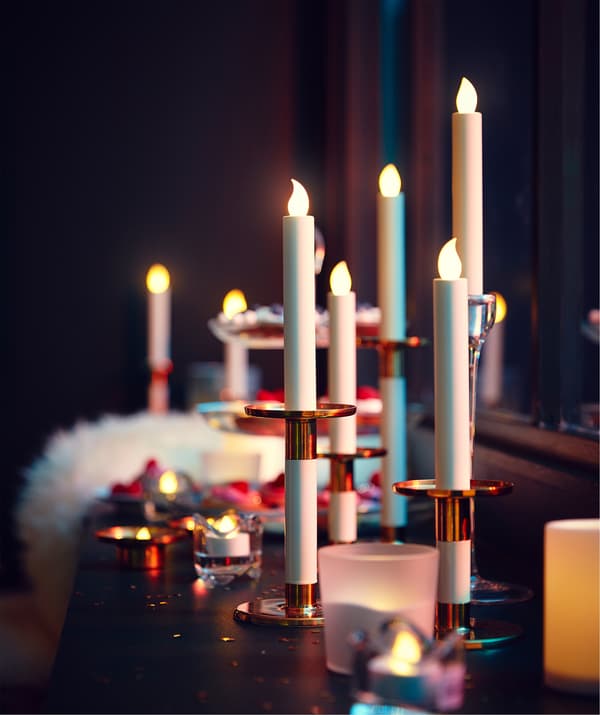 Parapeito profundo e longo densamente decorado com velas LED e velas pequenas, peles de ovelha para sentar e um prato de 3 andares com iguarias.