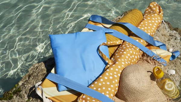 Parasol et coussin de lage posés sur un rocher au bord de l'eau