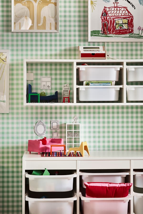 Pared cuadrille verde con blanco con muebles del  sistema de almacenaje infantil TROFAST. Se ven repisas con cajones y un mueble de piso con cajones.