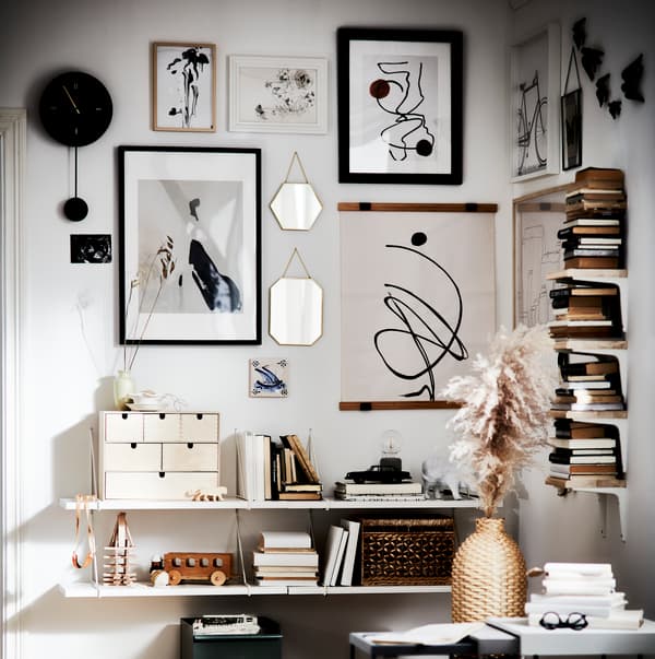 Pared decorada con muchos accesorios como cuadros, espejos, relojes, libros y más.