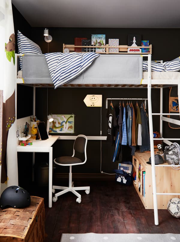 Part of a children’s room made up of a VITVAL loft bed and below it a study corner, a row of clothes on hangers, and storage.