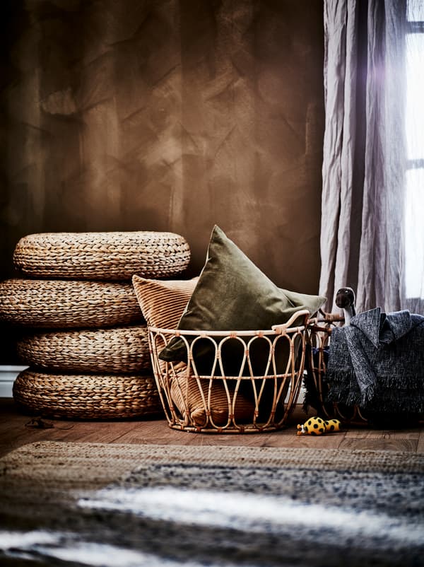 Parte de um quarto com um esquema de cores em tons de castanho-terra: parede castanha, cestos SNIDAD em rota, bancos ALSEDA e tapetes em materiais naturais.