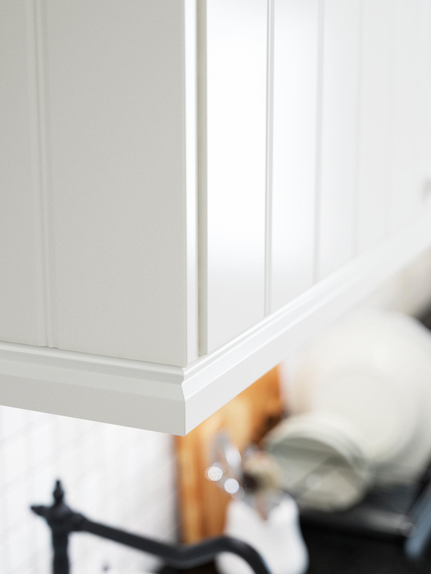 Partea de jos a unui dulap alb de bucătărie montat pe perete, cu o dungă conturată de decor.