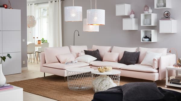 Pasztell színekben pompázó nappali két dohányzóasztallal, amely tárolóként is funkcionál.