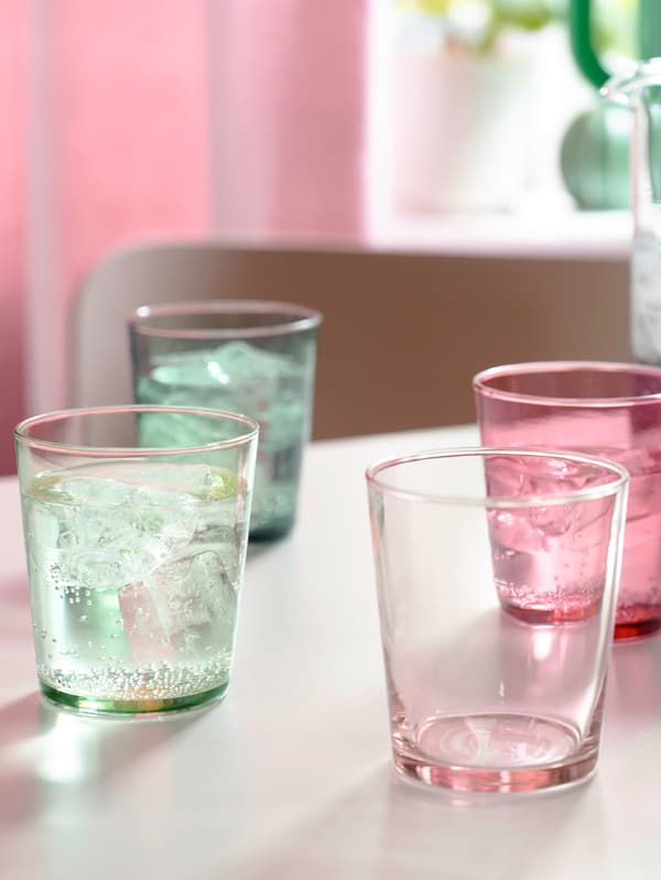 Pasztellszínekben pompázó PAPPERSBJÖRK üvegpoharak egy asztalon, mögöttük pedig rózsaszín falrészlet látható.