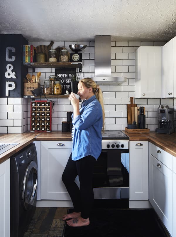 Pati standing in her white u-shaped kitchen that has a traditional style, but with cup handles and knobs in chrome.