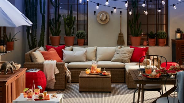 Patio yang mempunyai sofa luar dan meja lebih kecil berwarna putih dan bangku, meja makan dengan kerusi dan payung.