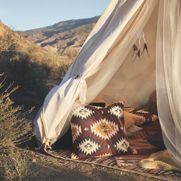 Patterned cushions and rugs in a tent outdoors.