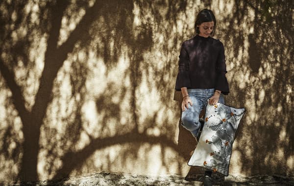 Paulin Machado holding a cushion with cactus print.