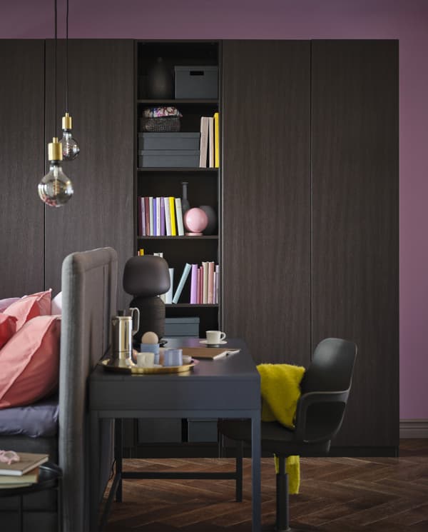 PAX/FORSAND wardrobe in black-brown with an open section where books stand. In front are a blue desk and a black chair.