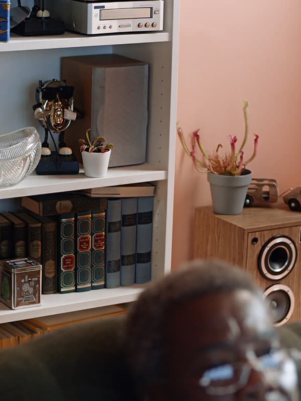 Pe un perete de culoarea piersicii se află o bibliotecă albă BILLY. Este plină cu cărți vechi, o boxă și articole diverse.