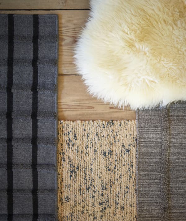Peau de mouton blanc cassé et tapis beige et gris superposés sur un sol brun clair