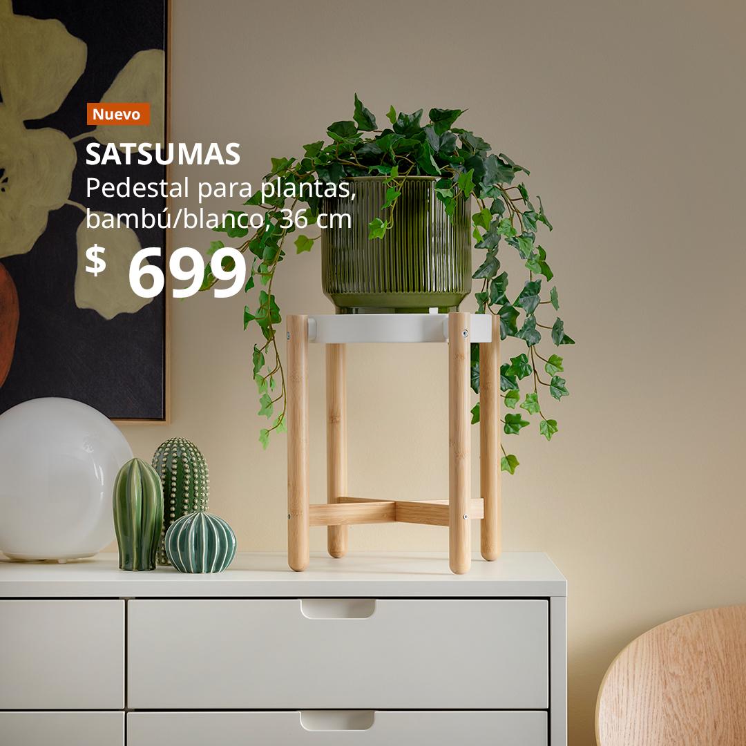 Pedestal para plantas SATSUMAS de bambú y color blanco, con una planta colgante en maceta, colocado sobre una cómoda.