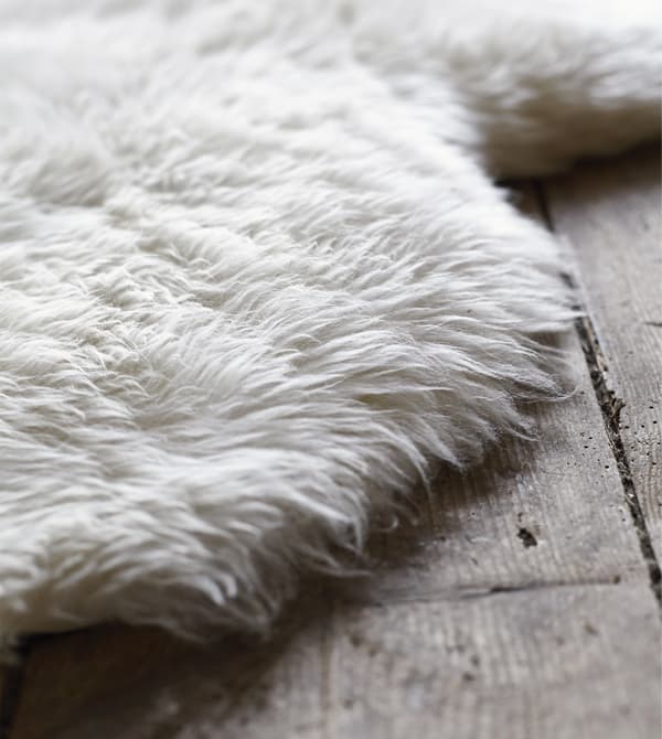 Pelle di pecora LUDDE usata come tappeto su un tappeto di legno.