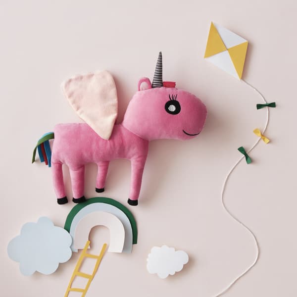 Peluche en forme de licorne rose dans un décor de ciel en papier.