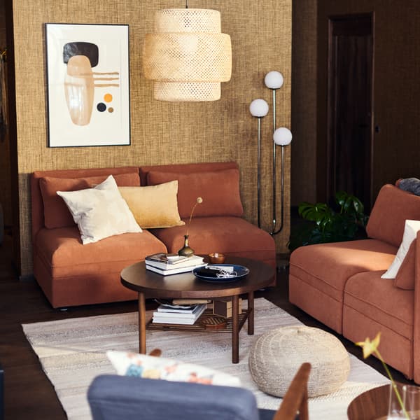 Penjuru ruang tamu yang mempunyai sofa, lampu dan terendak lampu gantung serta meja kopi.