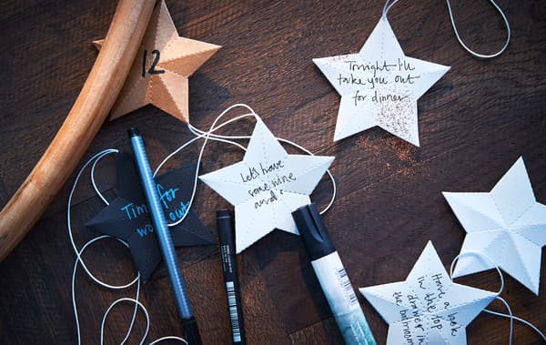 Pens and paper stars with notes written on them sit on a tabletop.