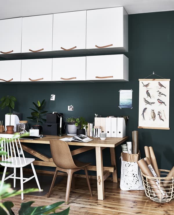 Pensili bianchi e un tavolo di legno contro una parete verde scuro.