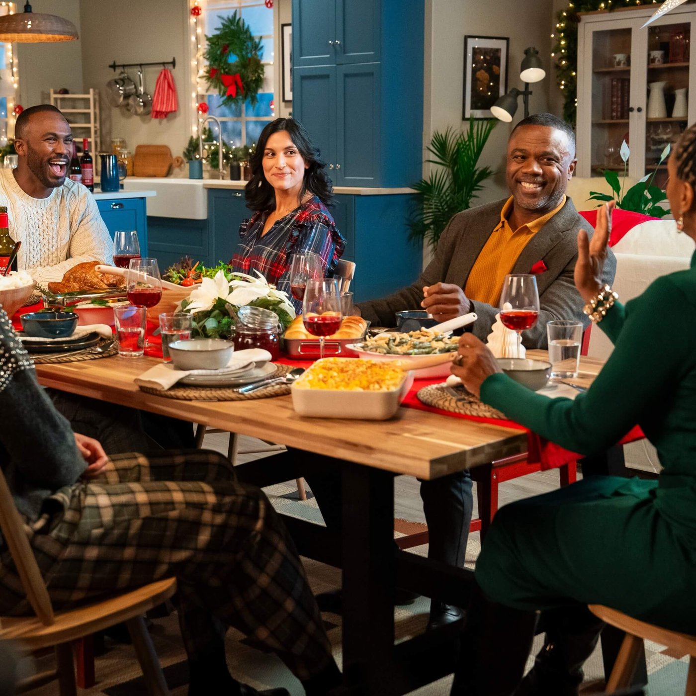 People gathered around a festive dining table with holiday decorations, enjoying a meal with various dishes and drinks.