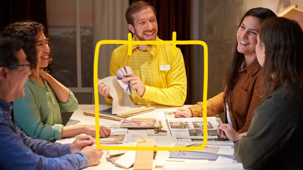 People gathered around a table discussing interior design materials and workspace solutions.