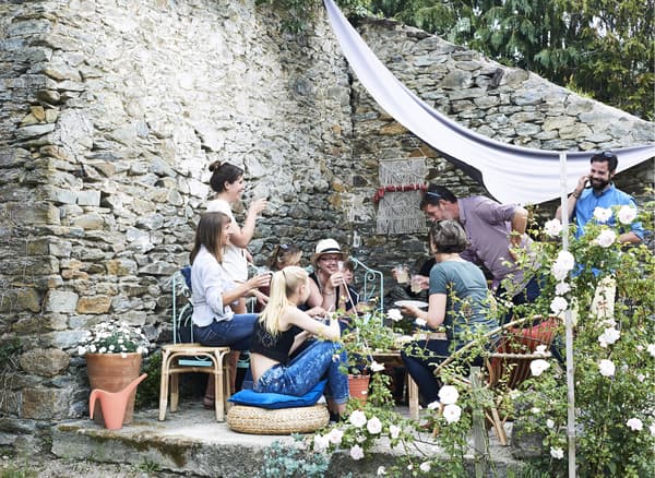 People gathered around with drinks in the walled garden.
